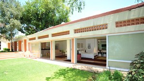 A modern building with a flat roof, large glass doors leading to a living area, and a well-maintained lawn. - Fifteen On Orange (Johannesburg)