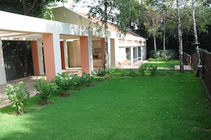 Enjoy a serene outdoor space with a covered patio and lawn, surrounded by lush shrubs and a beautiful view.