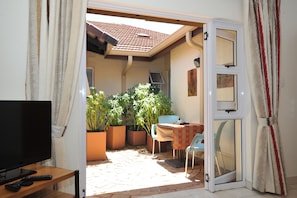 Patio luminoso con TV, posti a sedere e piante in vaso.