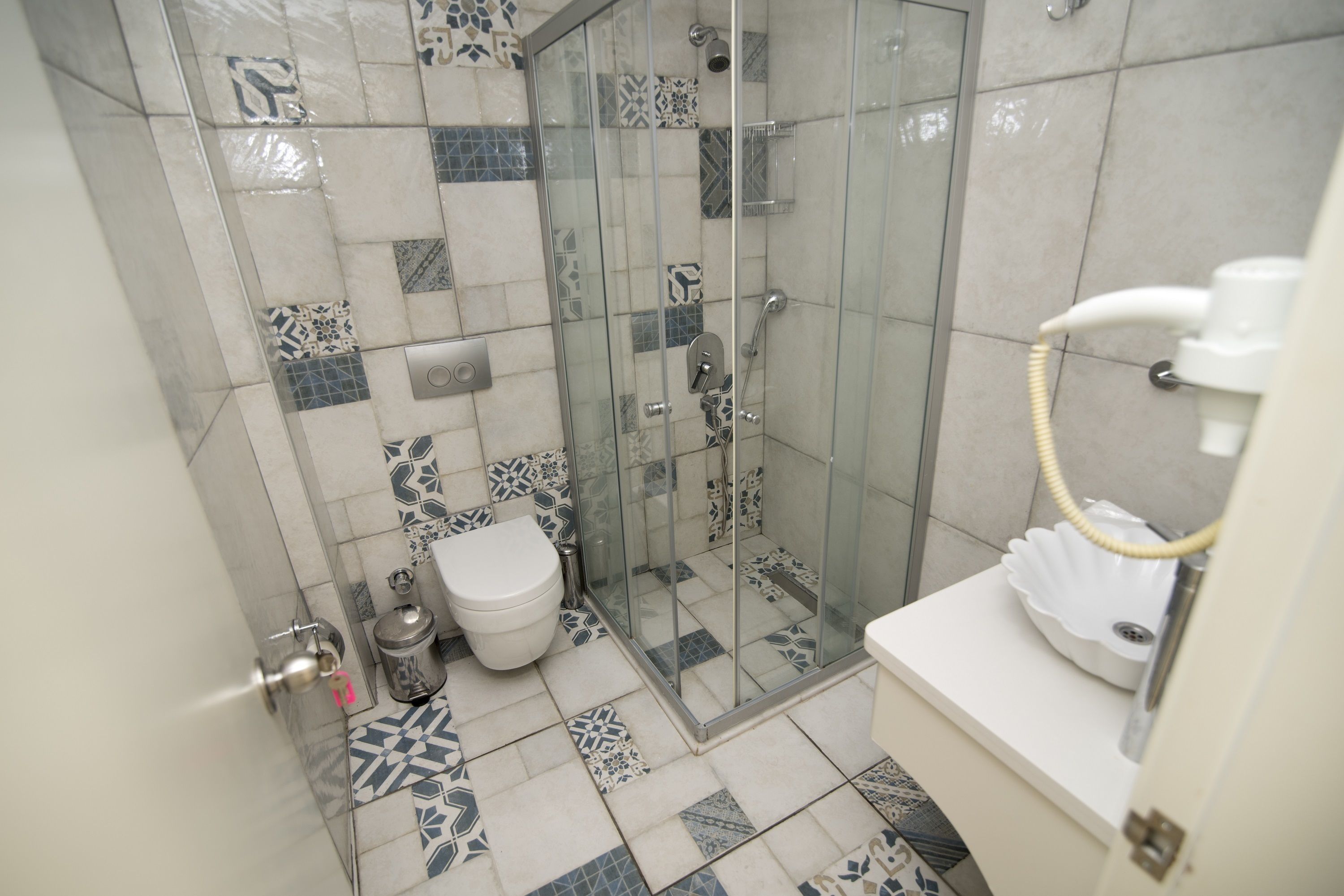 A bathroom with a glass-enclosed shower, a toilet, and a sink.