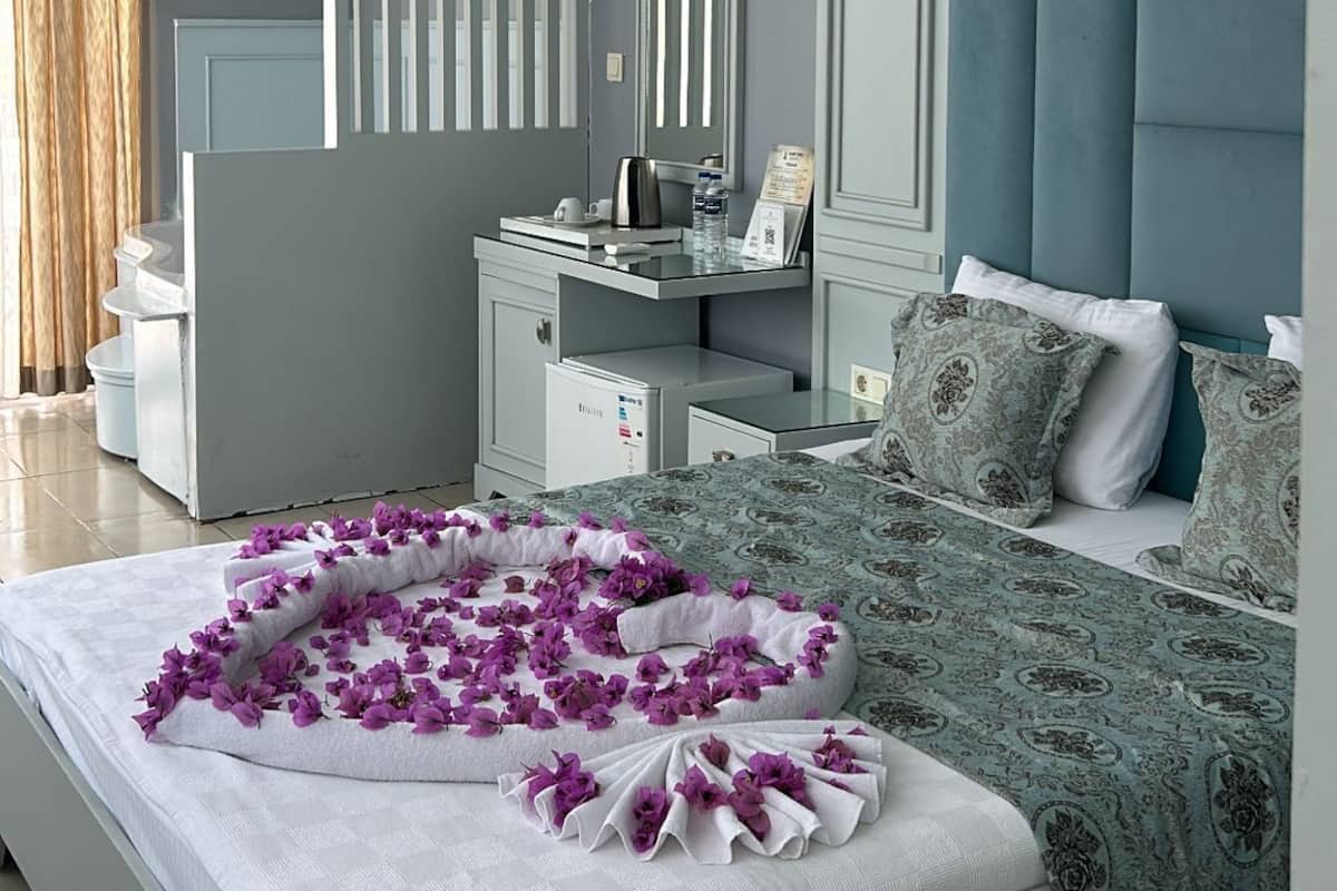A modern hotel room with a large bed, a vanity with a mirror, a bedside table, and a blue headboard.