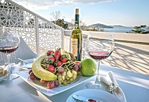 A table set with a bottle of wine, a glass of red wine, a plate of fruit, and a glass of white wine. - Buyukada Cankaya Hotel (Adalar)