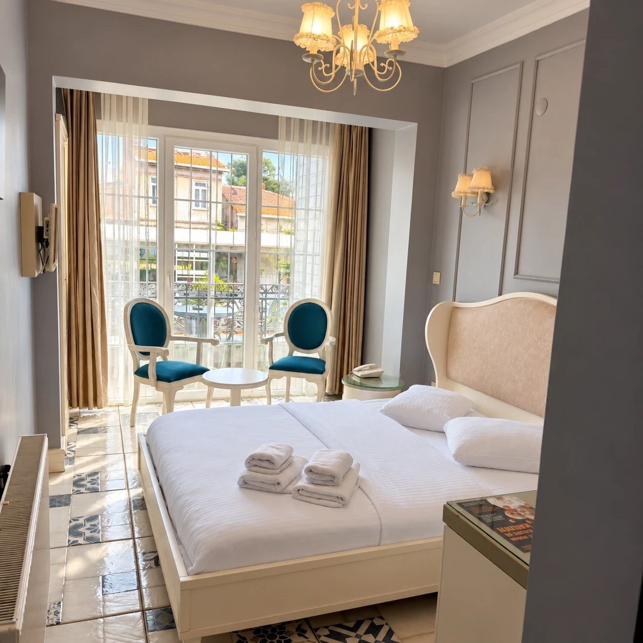 Une chambre d’hôtel avec un grand lit, deux fauteuils, une petite table, un piano et une vue sur l’extérieur.