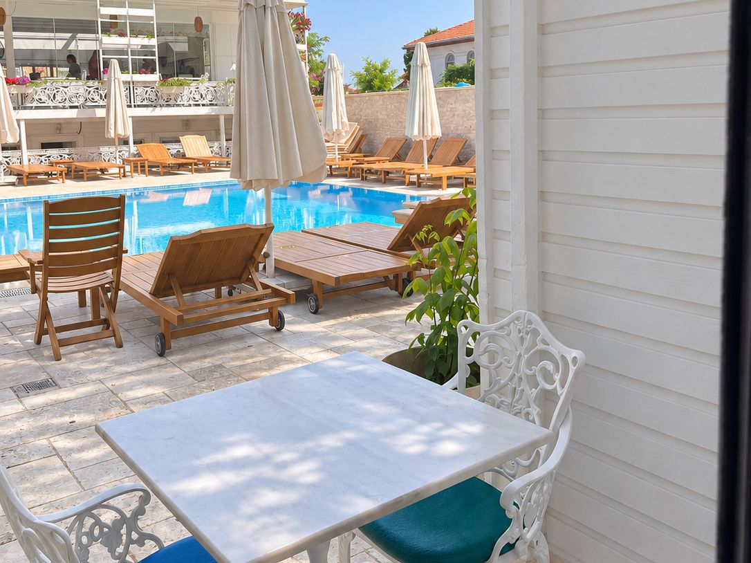 A poolside area with lounge chairs, a table, and umbrellas.
