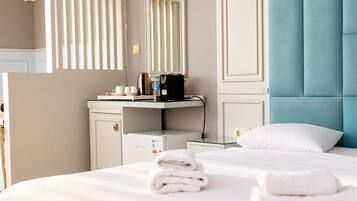 Une chambre d’hôtel comprenant un lit, une coiffeuse avec un miroir, une tête de lit bleue rembourrée et un climatiseur fixé au mur.