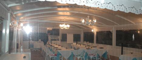 Un salón de banquetes con mesas dispuestas para comer, candelabros y un dosel de encaje.