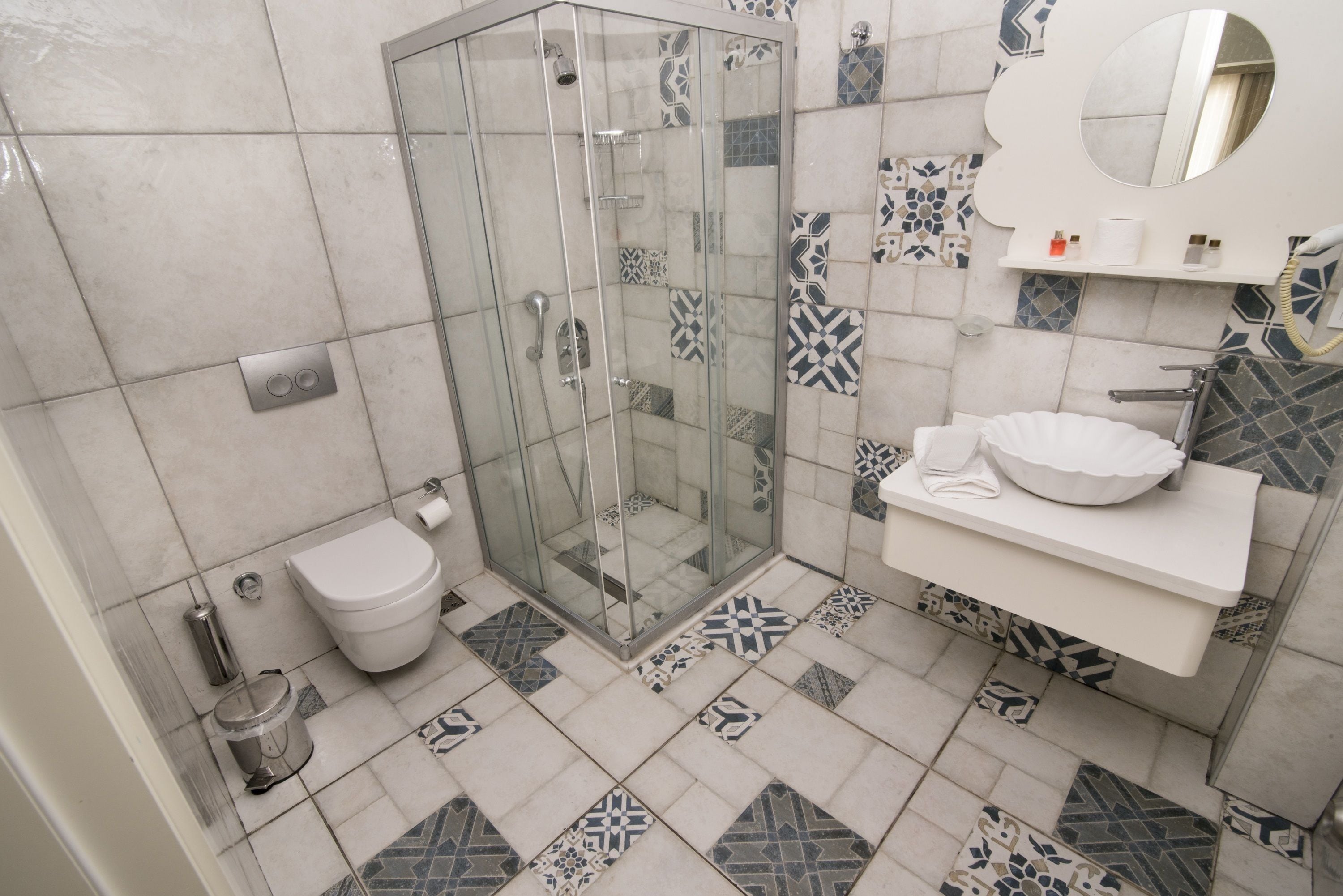 Un baño con ducha de vidrio, inodoro y lavamanos con espejo.