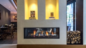 Un restaurant amb llar de foc, llibres a la paret i una pila de llenya.