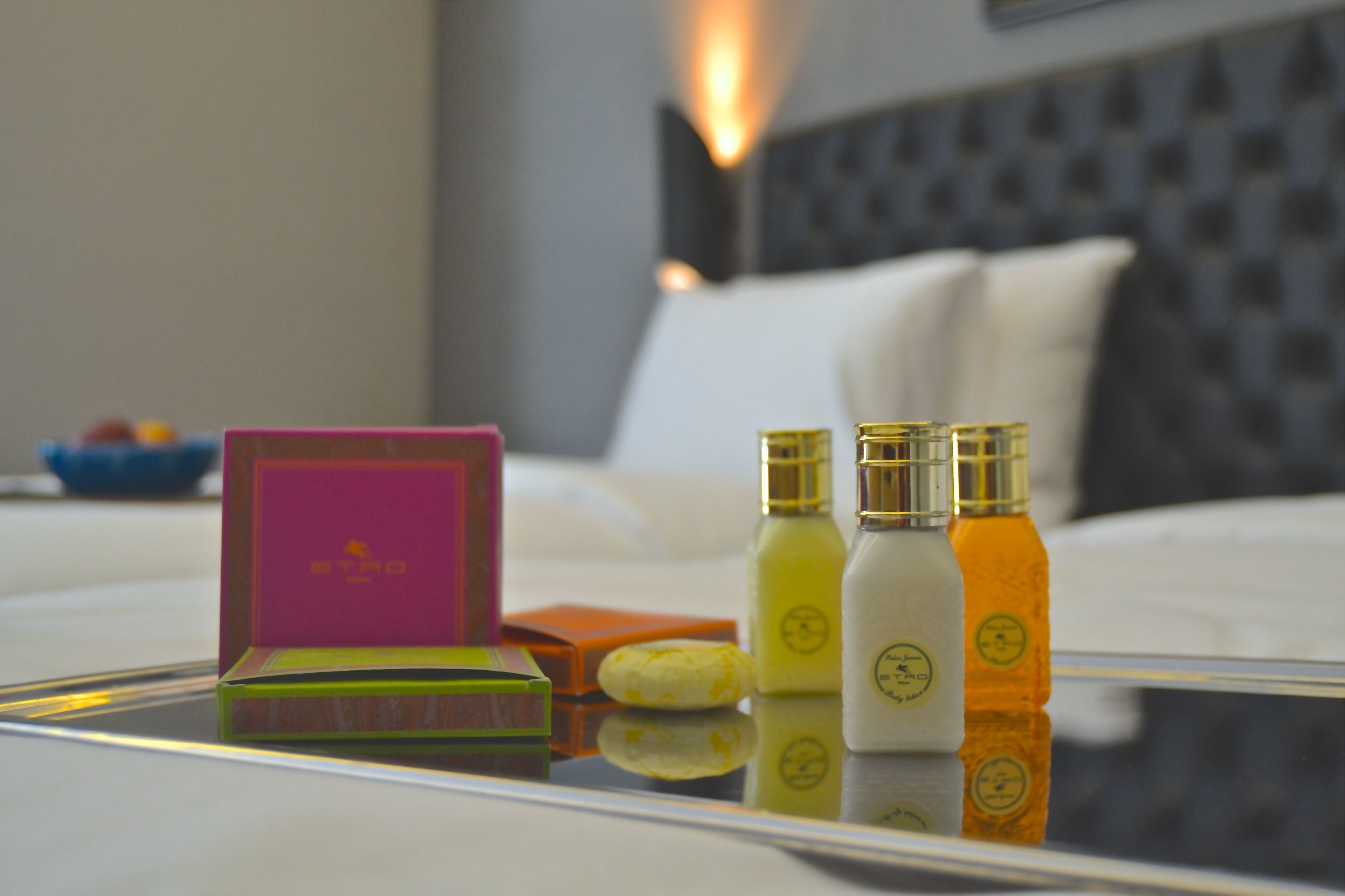 A neatly arranged table with a pink box, a green box, and three bottles with gold caps.