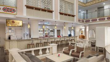 A spacious lobby with a bar area, seating arrangements, and a decorative ceiling.