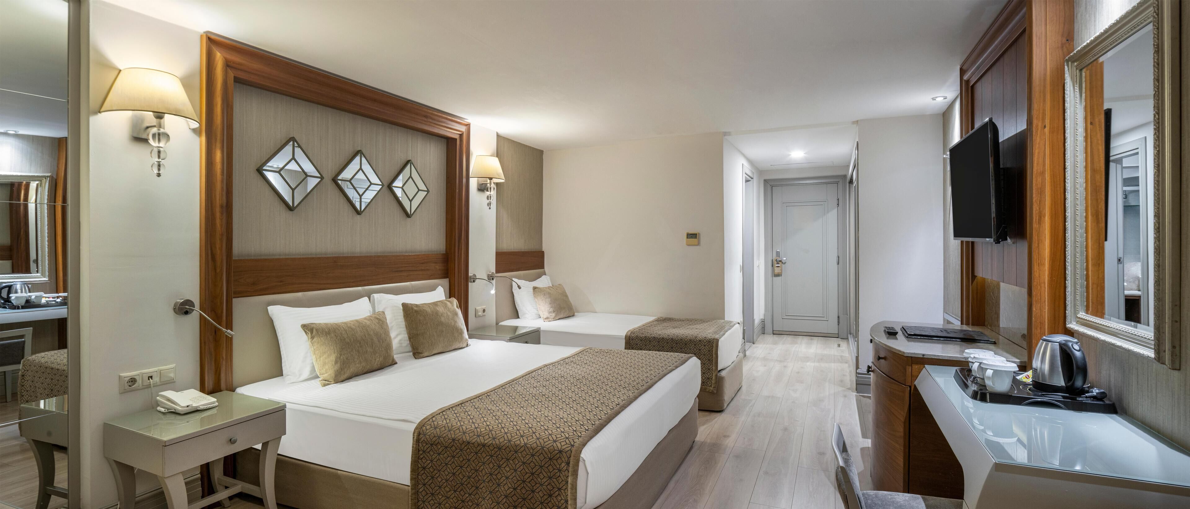 Una habitación de hotel con dos camas, un escritorio, un televisor y un espejo.
