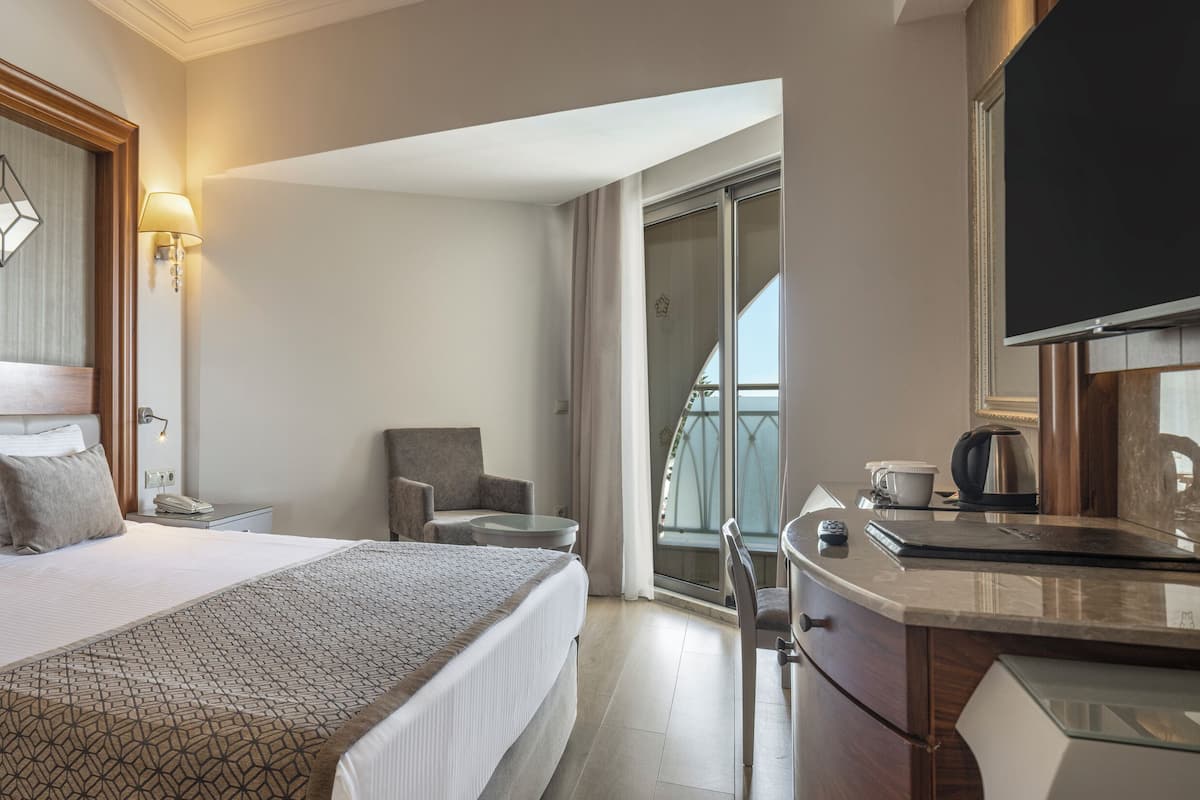 Una habitación de hotel con una cama grande, mesitas de noche, un escritorio, una silla y un televisor.