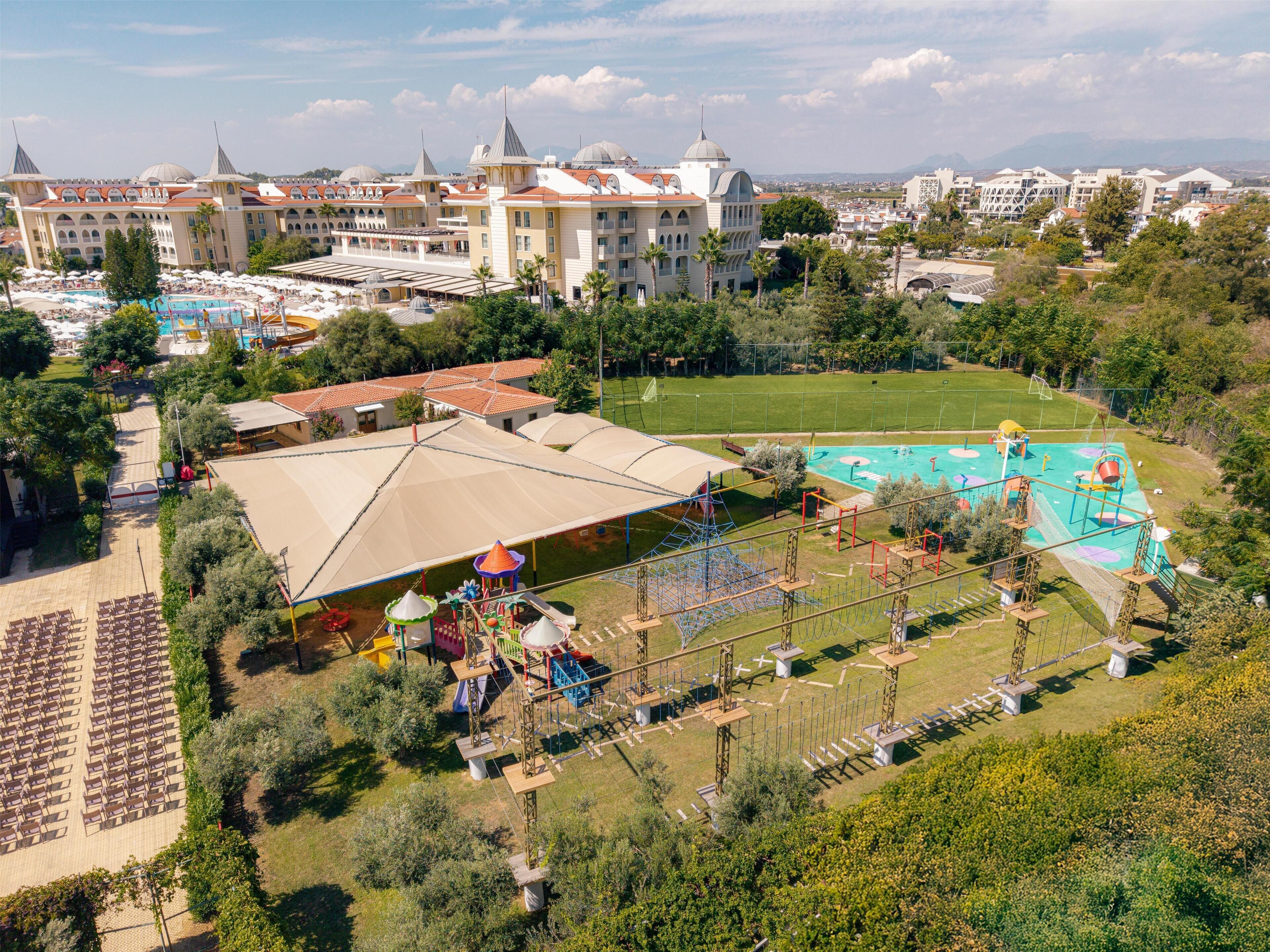 A resort with a large pool, outdoor seating, and a playground.