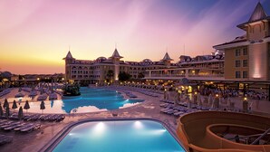 A resort with a large pool, multiple dining areas, and a grand building with towers.