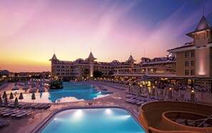 A resort with a large pool, multiple dining areas, and a grand building with towers.