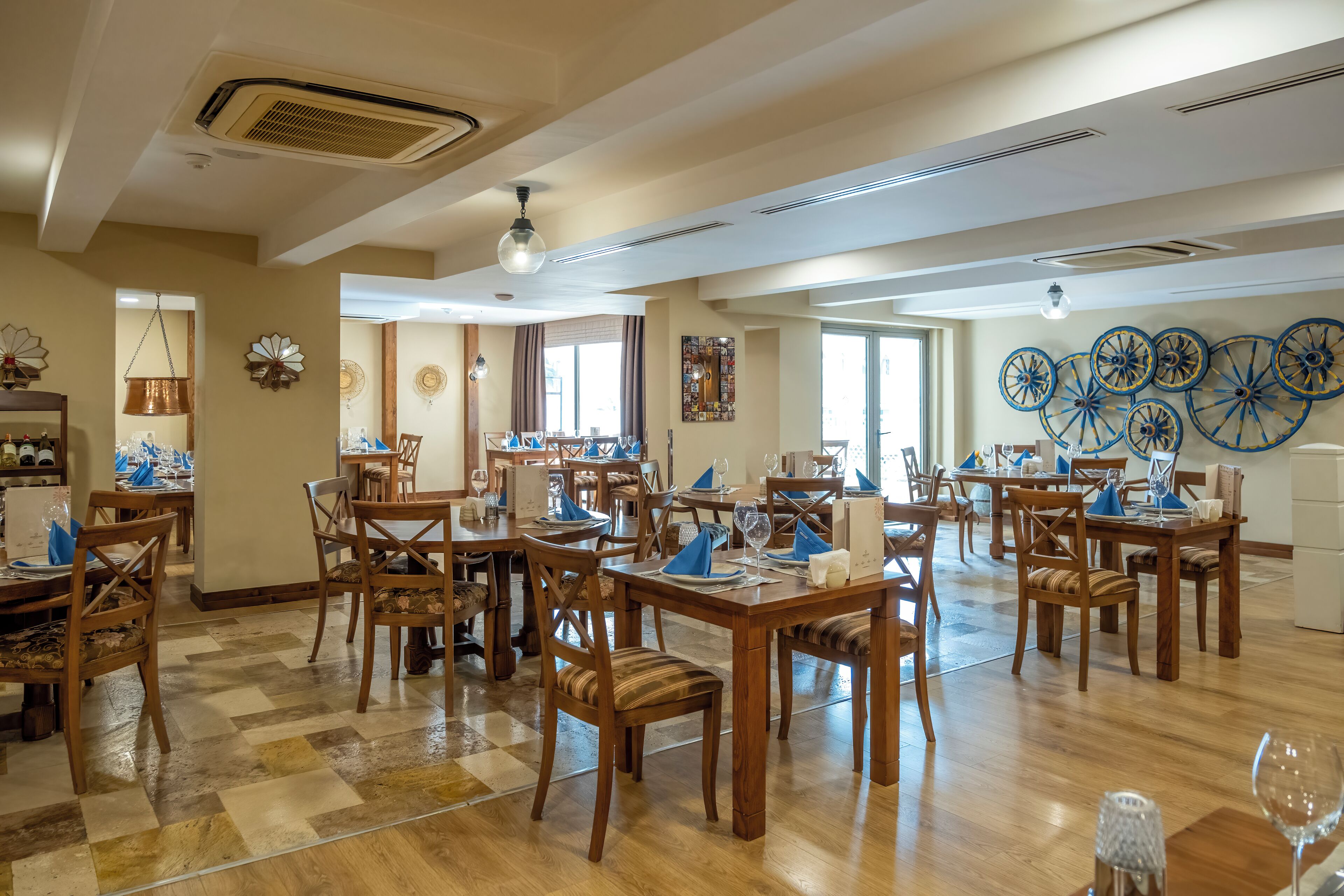 A spacious dining area with multiple wooden tables and chairs, arranged in a U-shape.