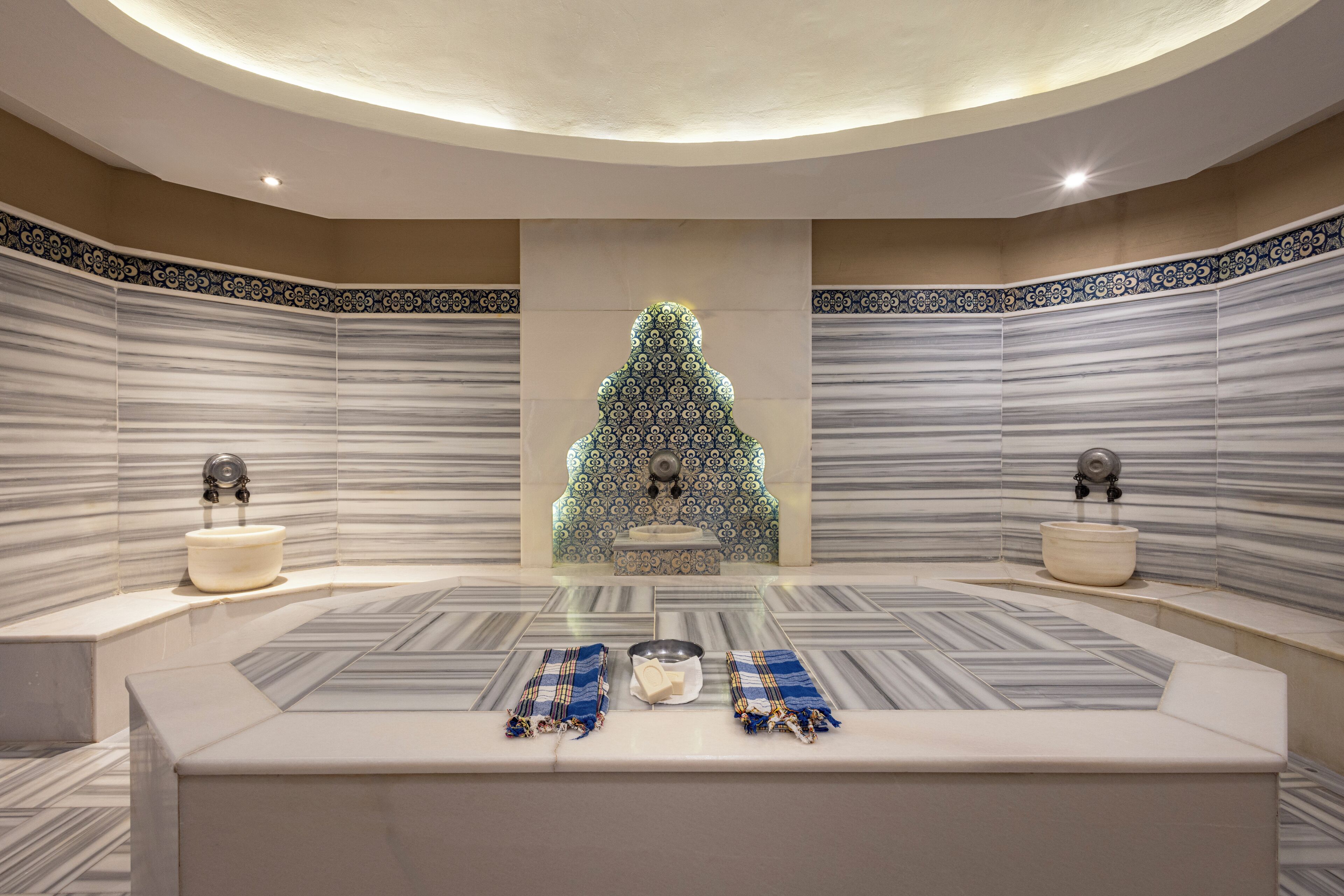A modern bathroom with a central sink, two towel racks, and a patterned floor.