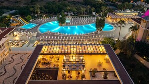 A resort with a large swimming pool, sun loungers, and a view of the ocean.