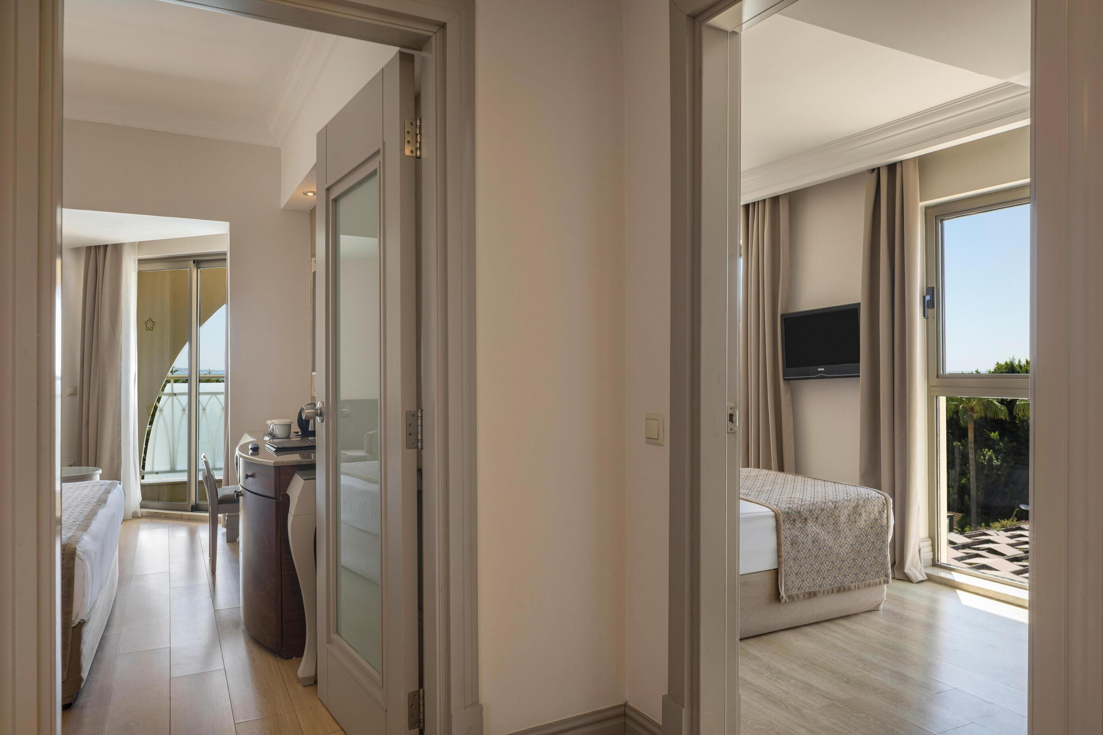 A hotel room with a bed, a desk, a chair, a TV, and a balcony with a view.