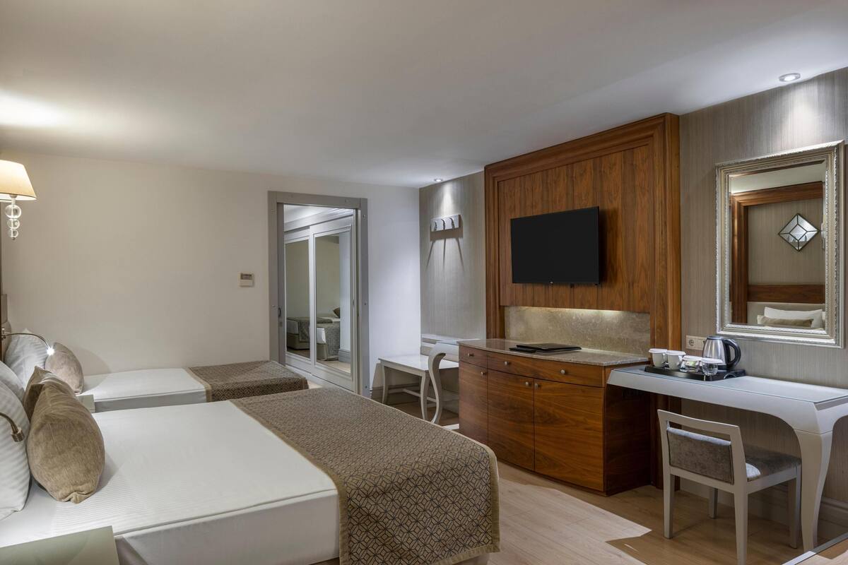 Una habitación de hotel con cama, escritorio, silla, televisor y armario.