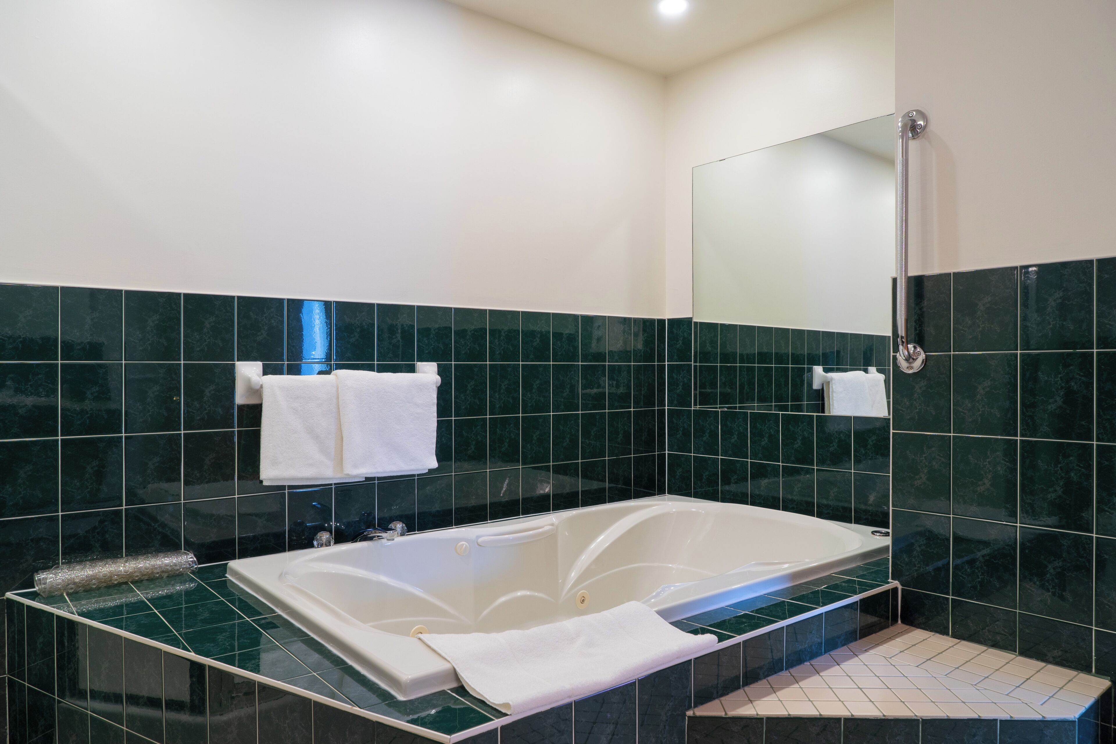Un baño moderno con una bañera con mampara de vidrio, zona de ducha y un espejo.