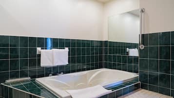 Un baño moderno con una bañera con mampara de vidrio, zona de ducha y un espejo.