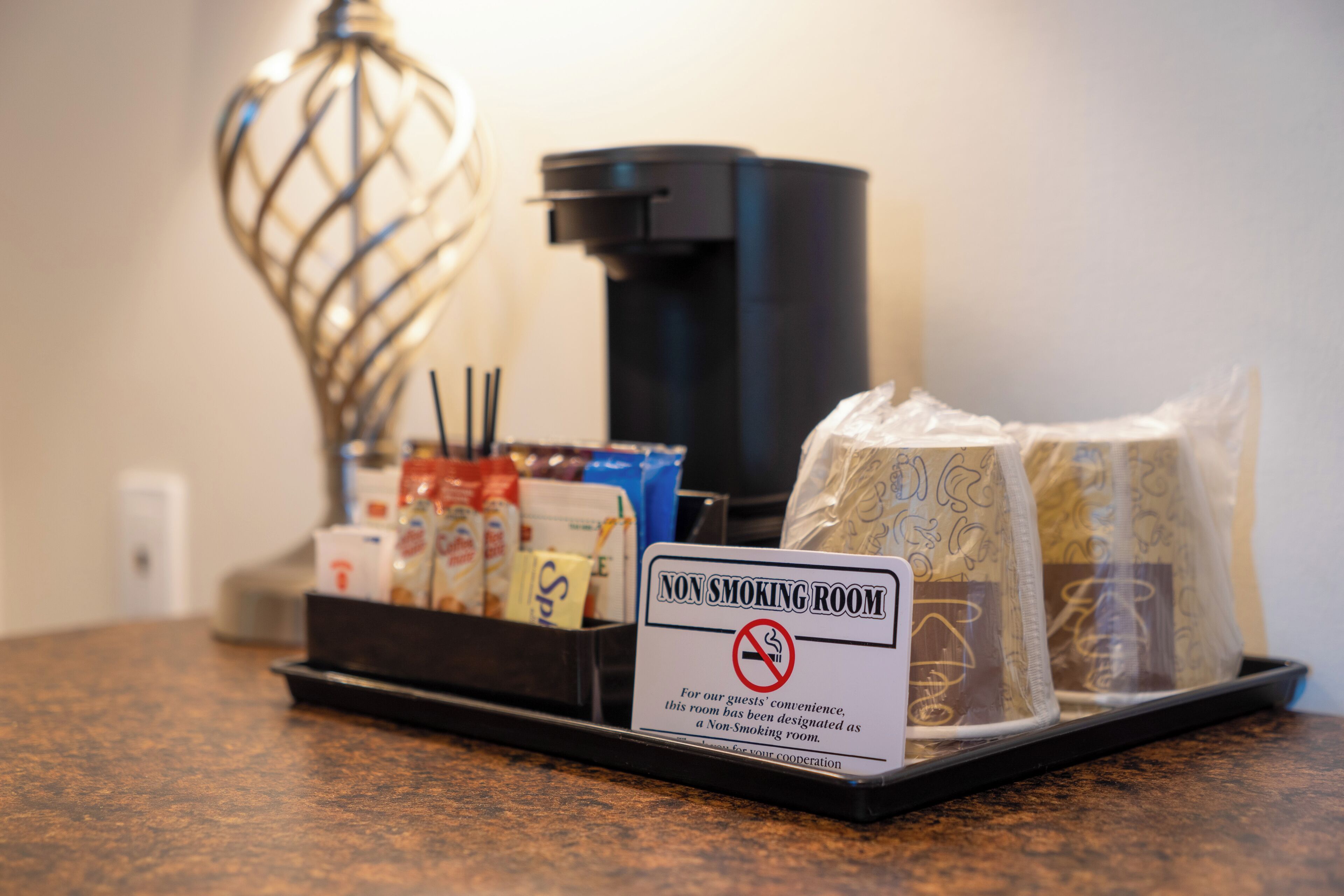 A non-smoking sign, a coffee machine, and packaged snacks on a counter.