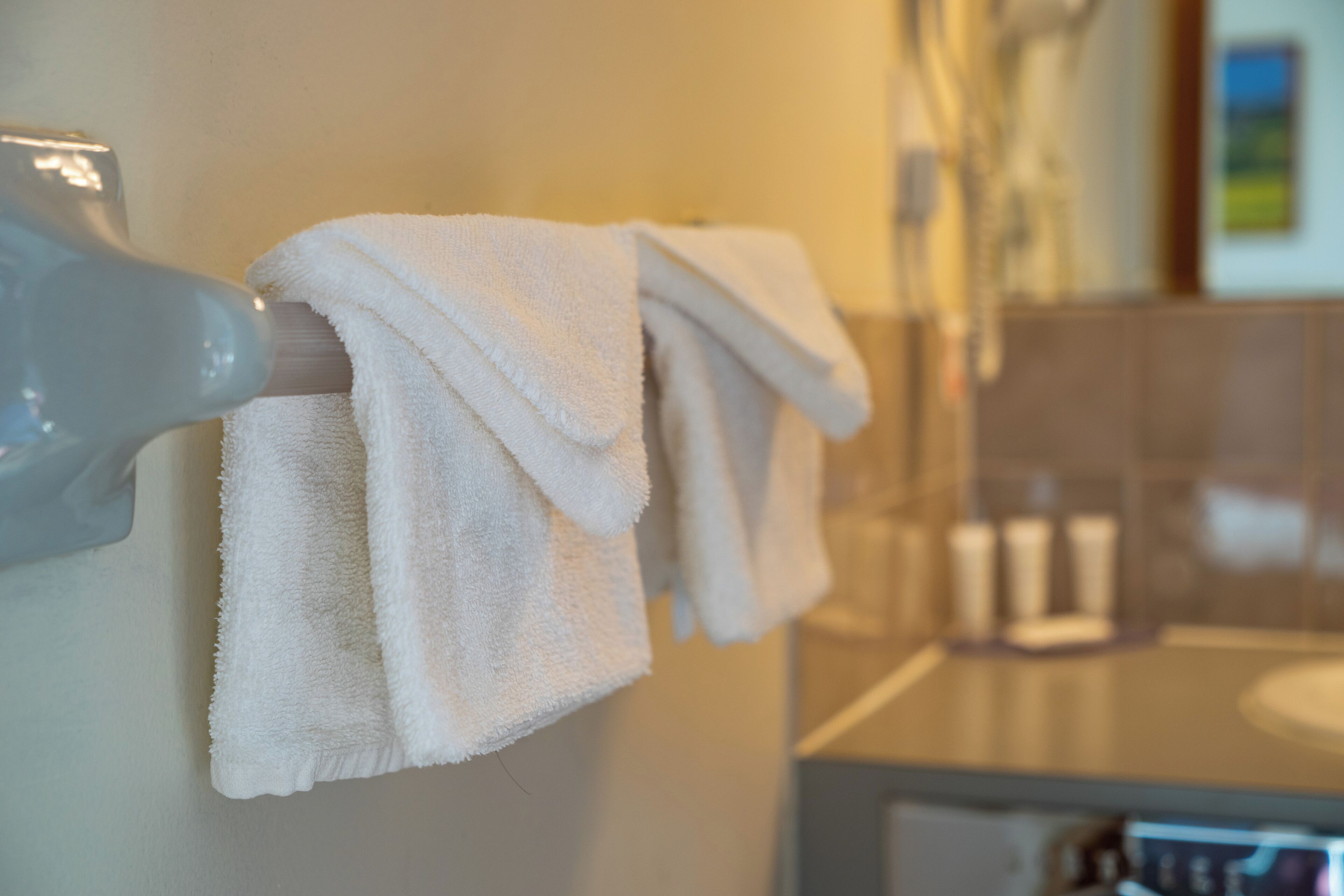 A bathroom with a towel rack holding two towels, a mirror, and a sink.