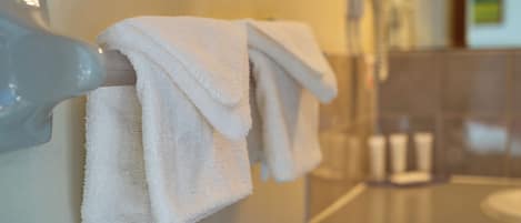 A bathroom with a towel rack holding two towels, a mirror, and a sink.