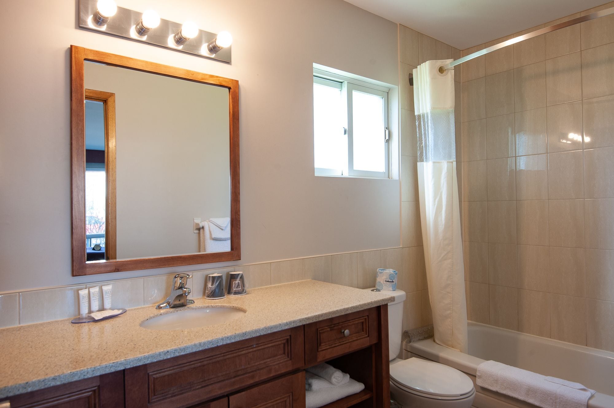 A bathroom with a sink, mirror, vanity, and shower area.