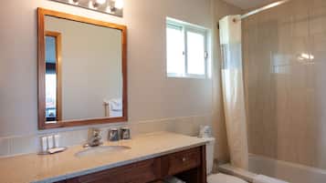 A bathroom with a sink, mirror, vanity, and shower area.