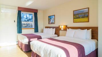 A hotel room with two beds, a window with curtains, a painting on the wall, and a wooden floor.