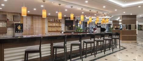Un bar moderno con diversas opciones de asientos e iluminación colgante.