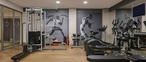 A gym with various exercise equipment, including treadmills, stationary bikes, and weight machines.