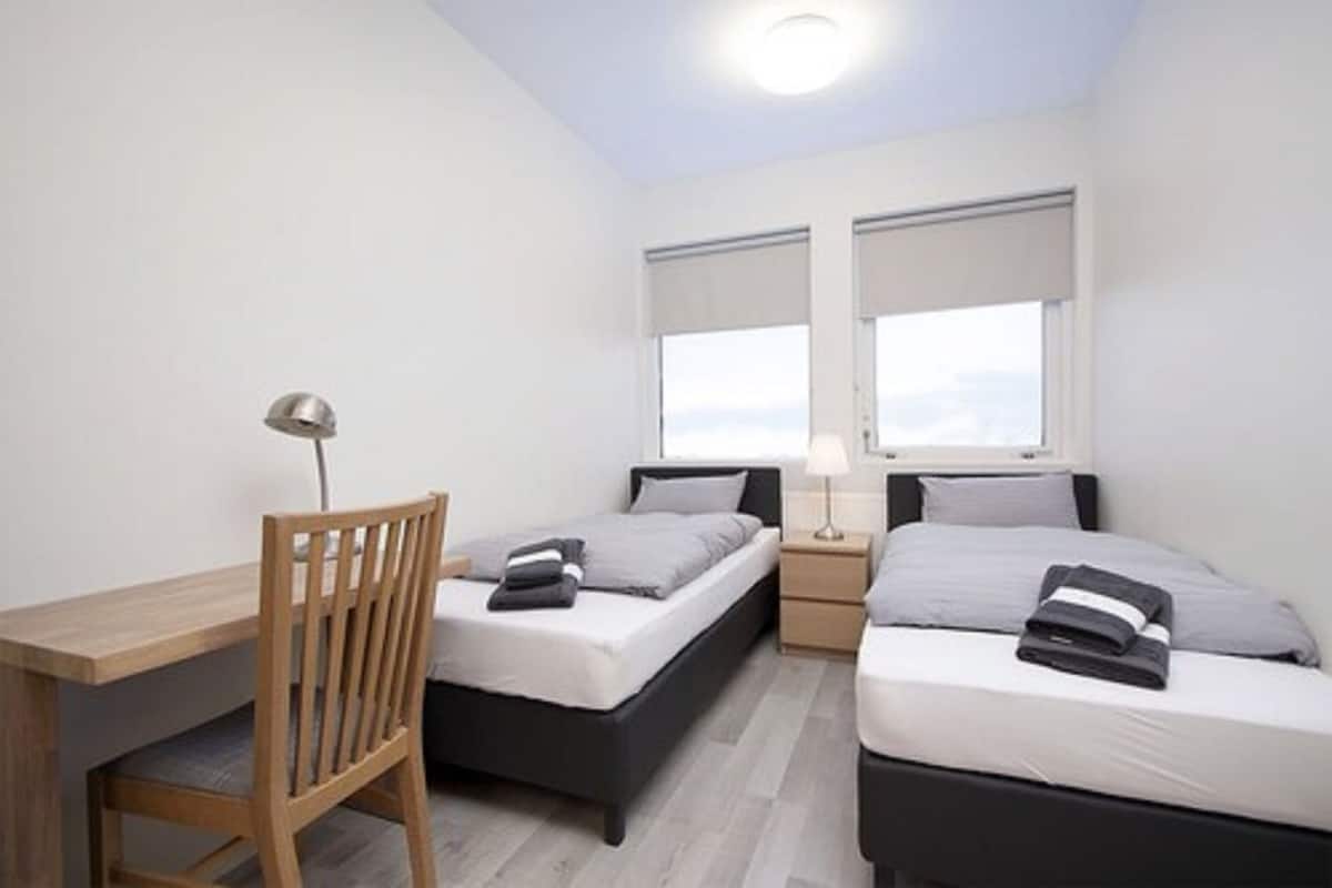 A bedroom with two beds, a desk, and a chair.