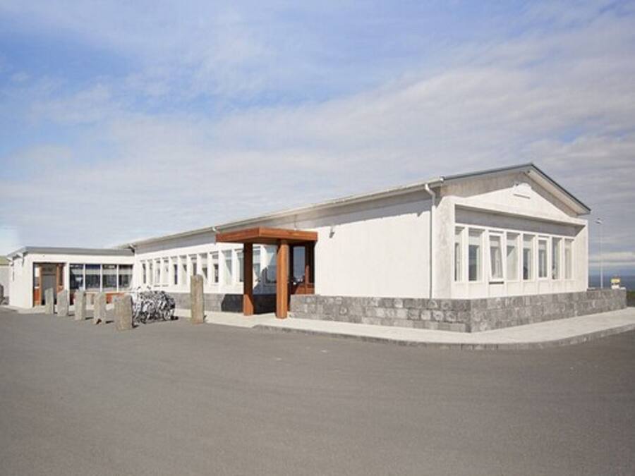 A building with a covered entrance, a stone base, and a flat roof.