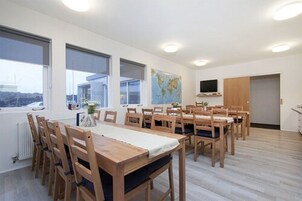 Un amplio comedor con mesas y sillas de madera, ventanas grandes y un mapa mundial en la pared.