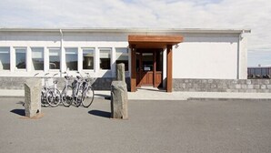 A building with a white facade, a wooden entrance canopy, and a row of bicycles parked outside.