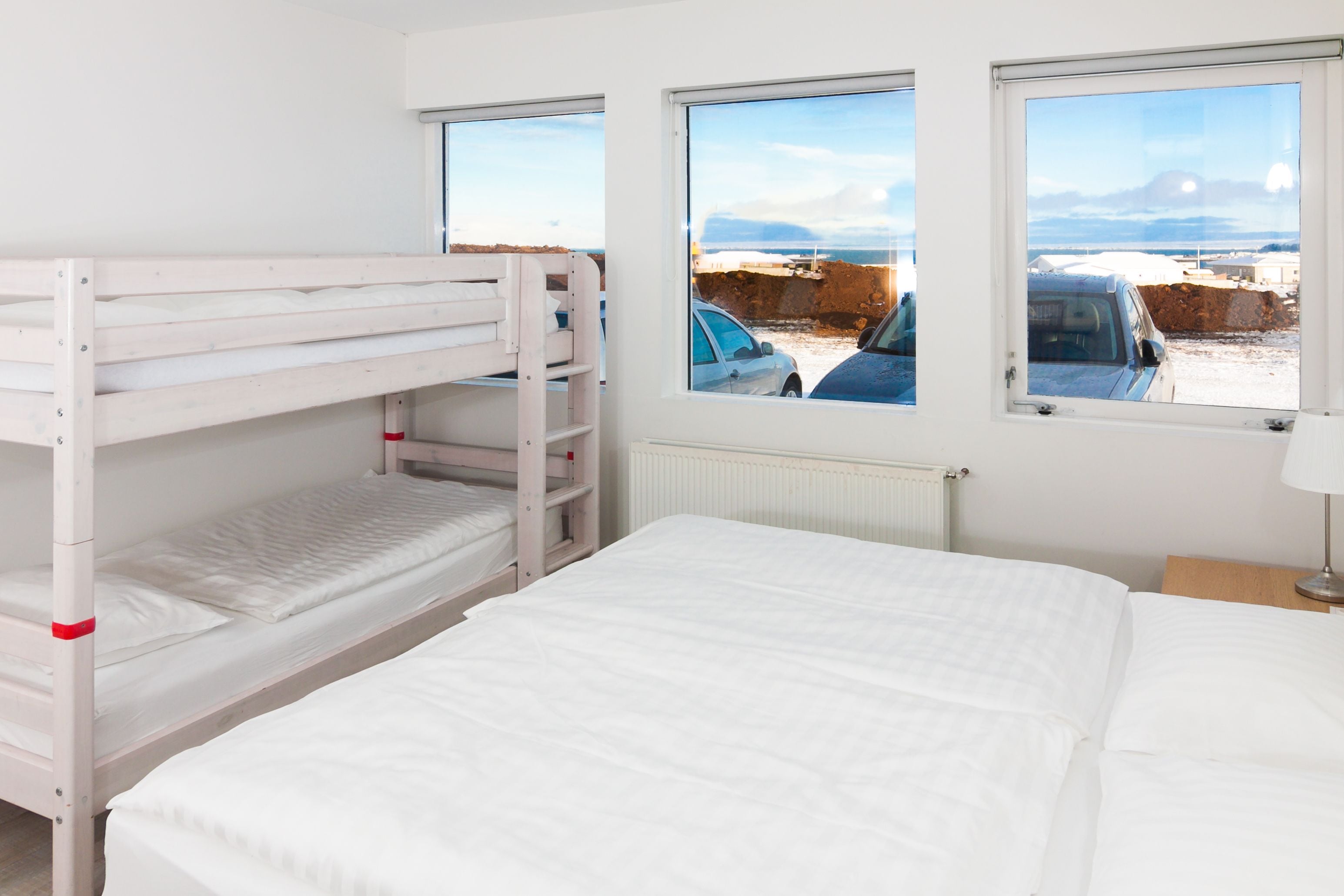 A bunk bed room with a large window and a view of a parking area.