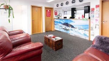 A reception area with a wooden desk, a large wall mural, and red leather seating.