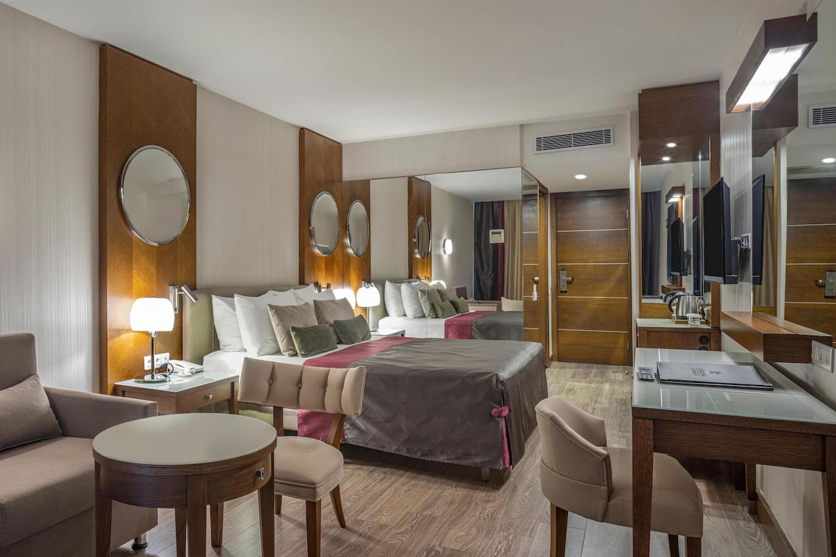 A hotel room with a bed, a desk, a chair, a round table, and a sofa.