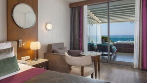 A hotel room with a bed, a desk, a chair, a round mirror, a lamp, and a view of the ocean through a sliding glass door. - Side Star Elegance Hotel - Ultra All Inclusive (Manavgat)