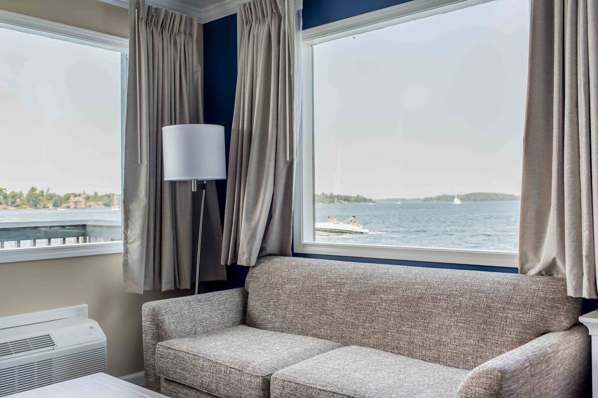 A room with a sofa, a lamp, and a view of the water.