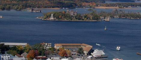 A coastal town with a prominent building with a flat roof, a dock with boats, and a large body of water.