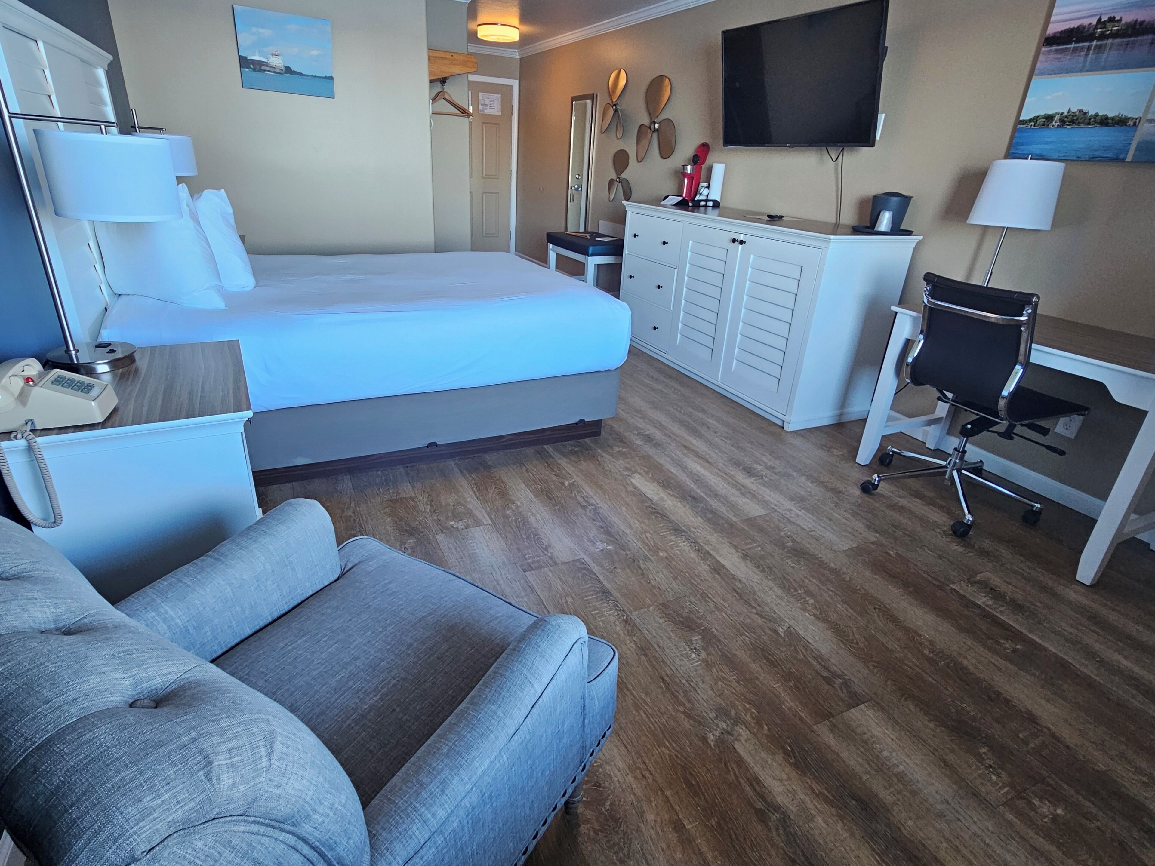 A hotel room with a bed, a desk, a chair, a TV, and a wardrobe.