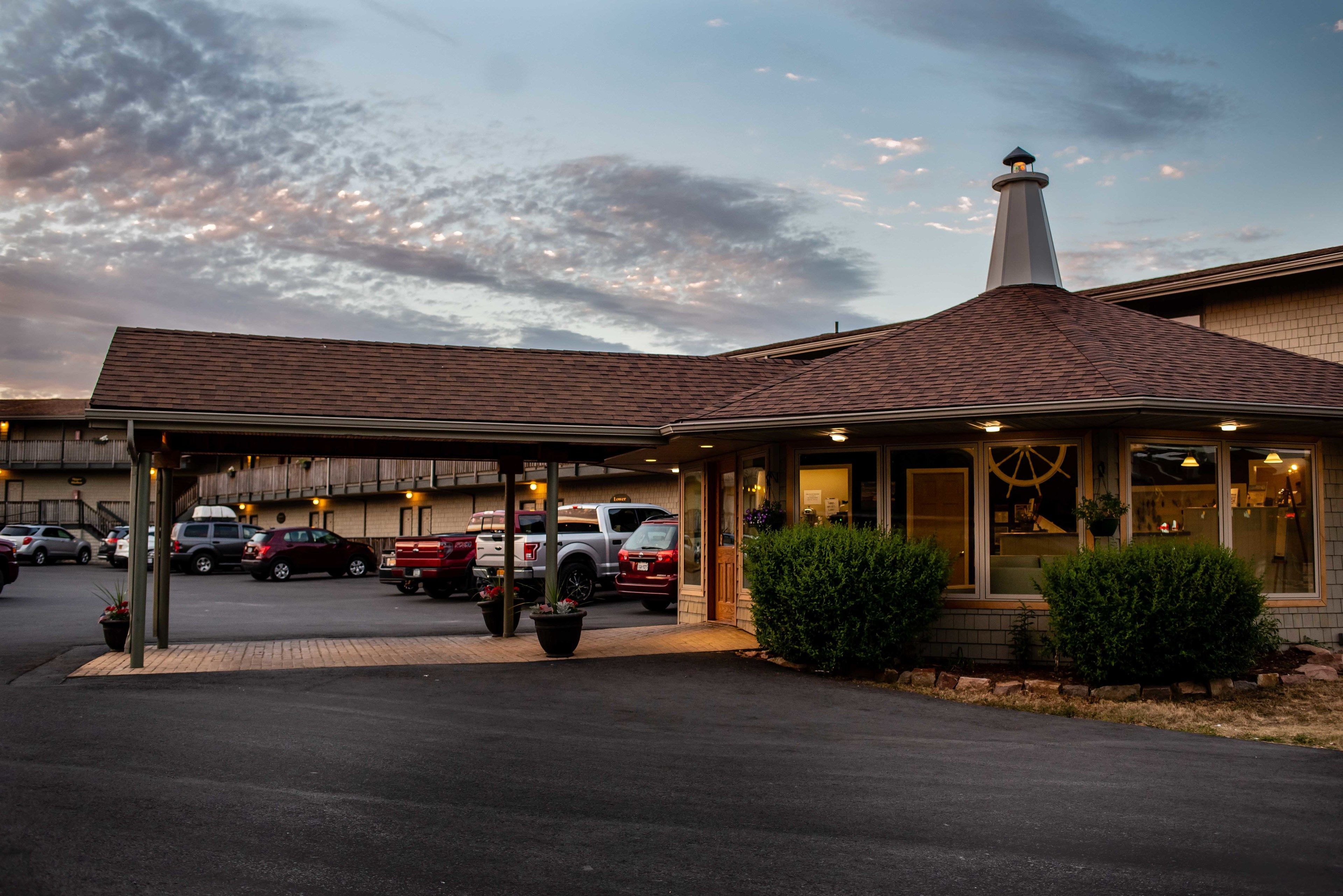 A hotel with a covered parking area, a chimney, and a building with a large window.