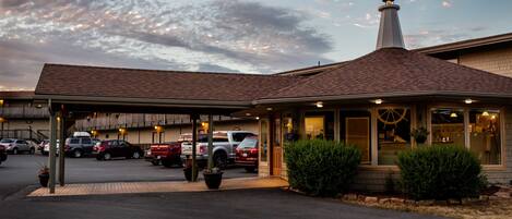 A hotel with a covered parking area, a chimney, and a building with a large window.