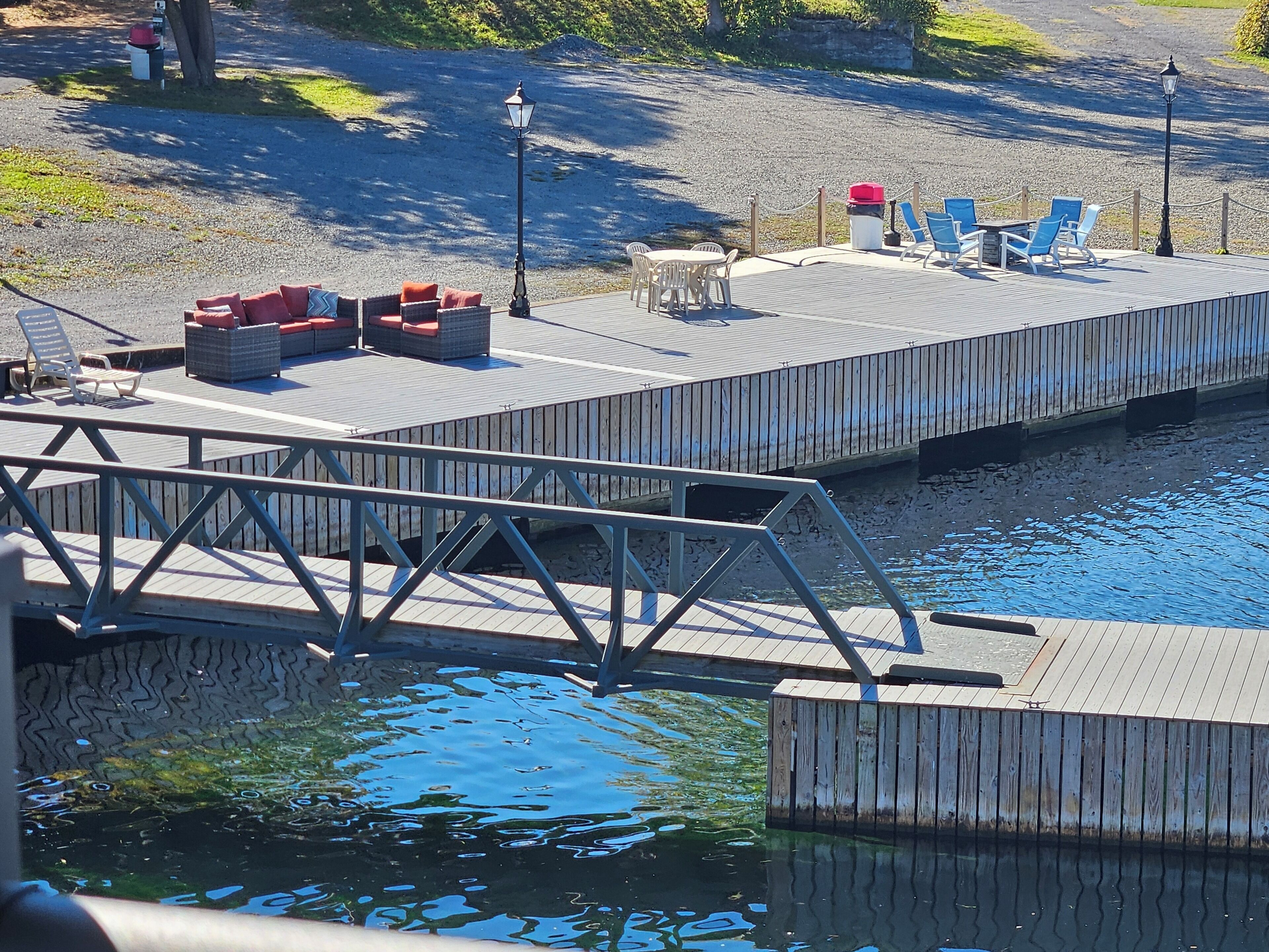 A wooden dock with seating and tables, extending over a body of water.