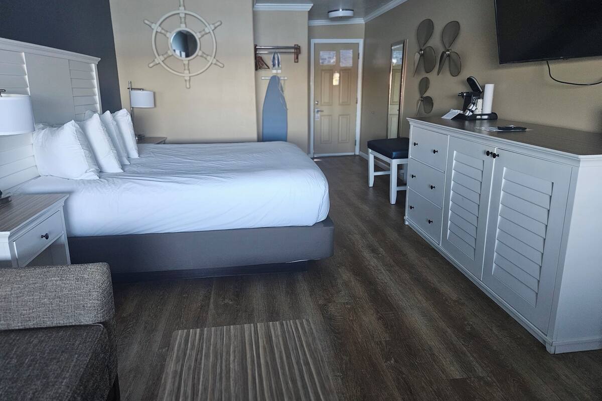 A hotel room with a bed, a desk, a chair, a TV, and a wardrobe.