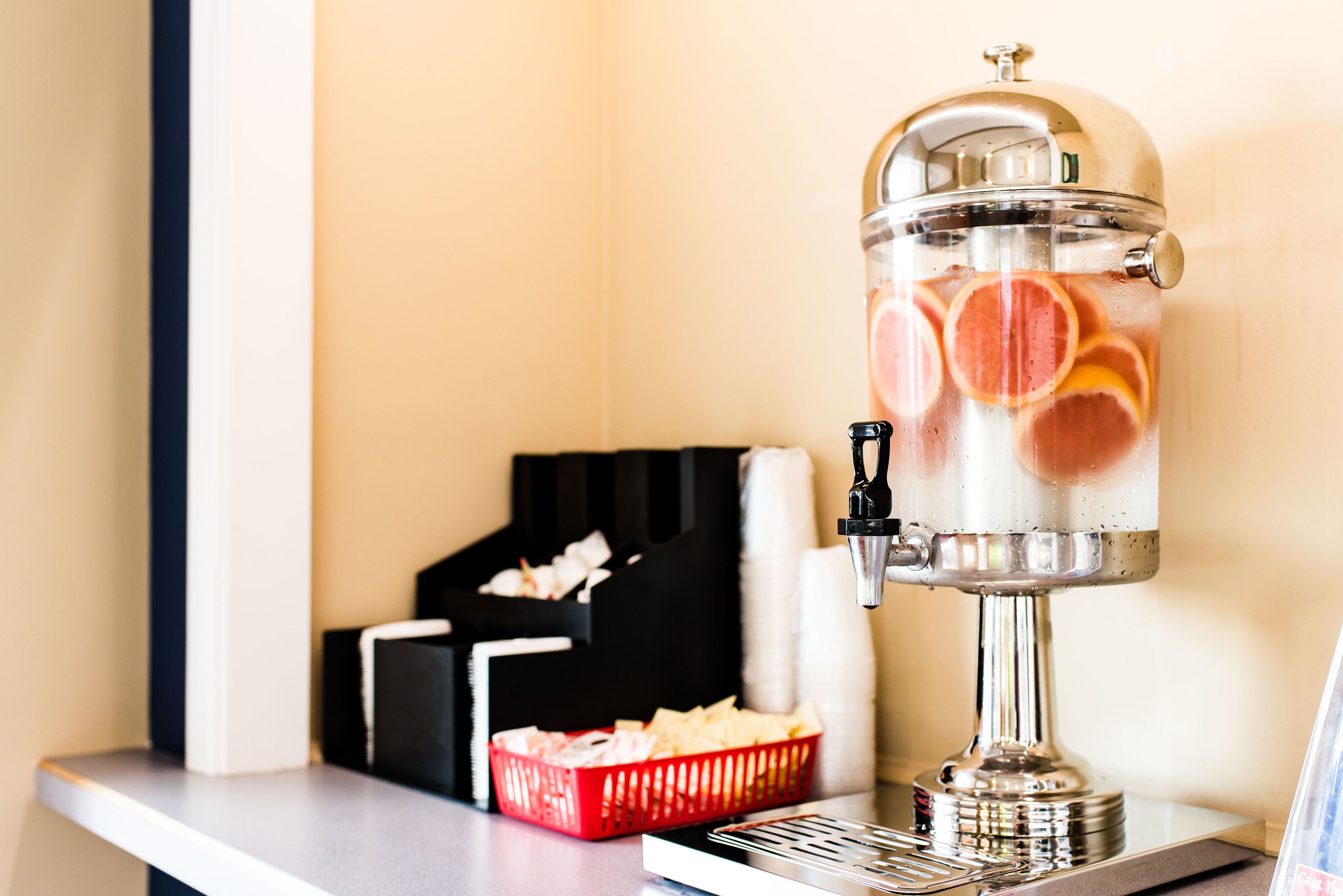 Een drankdispenser met een transparant bovenwerk, gevuld met plakjes citrusfruit.